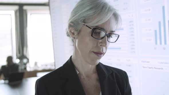 Greyhaired Businesswoman in Glasses Holding Tablet and Typing alt
