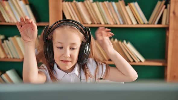 Closeup Portrait of Little Happy Child Girl Dancing on Sofa While Listening Music in Headphones in