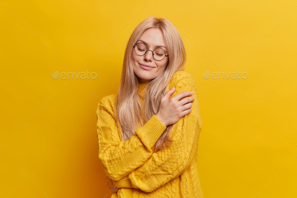 Selfish emotion concept. Pleased relaxed blonde European woman hugs herself gently expresses self lo