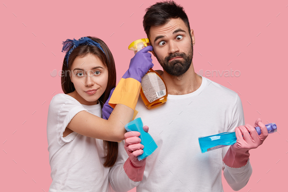 Funny unshaven man crosses eyes, helps wife with cleaning house, work together, do domestic chores,