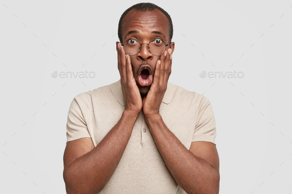 Indoor Shot Of Stunned Dark Skinned Male Has Excited Face Expression