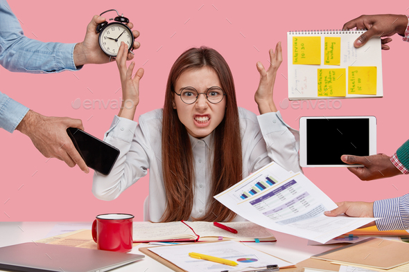 Peevish woman holds hands in disgust, being overwhelmed with much work, feels pressure from colleagu - Stock Photo - Images