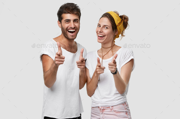 Body language concept. Positive young woman and man with joyful expressions, point at camera as if c