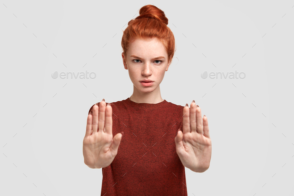Leave me in peace, please! Don`t bother! Angry red haired female pulls palms at camera, shows stop g