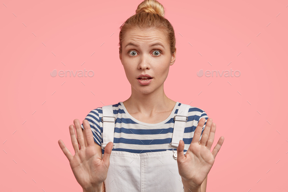 European blonde female poses with outstretched hands, demonstrates stop gesture, asks to halt, has s