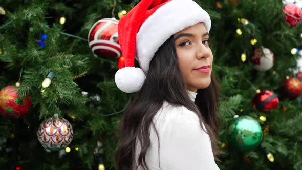 Attractive woman in a Santa hat celebrating the holiday season with a Christmas tree ornaments and l alt