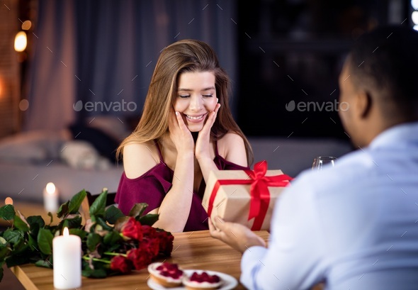 Happy International Women\'s Day. Loving Black Man Giving Gift To Excited Girlfriend