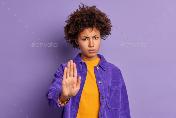 Serious annoyed dark skinned Afro American woman keeps palm in stop gesture asks not to bother her l