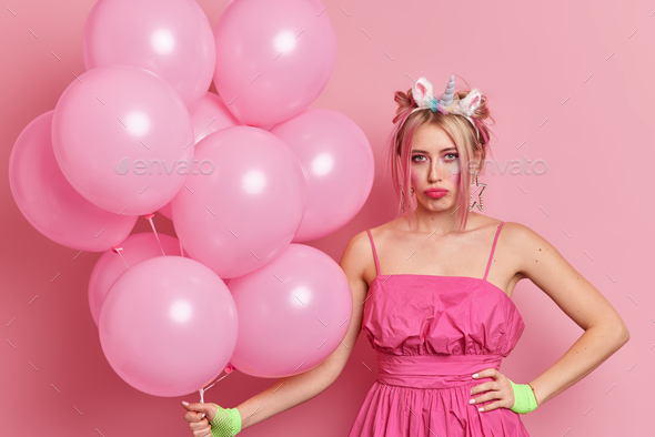 Unhappy woman upset something went wrong on party wears pink festive dress has trendy hairstyle brig