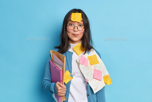 Pretty schoolgirl prepares for math test crams material has sticker on forehead not to forget necess