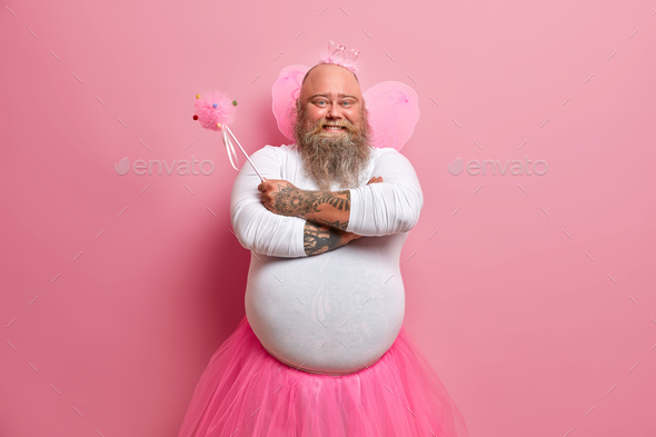 Cheerful confident bearded bald man fairy going to make your wish come true holds magic wand wears w
