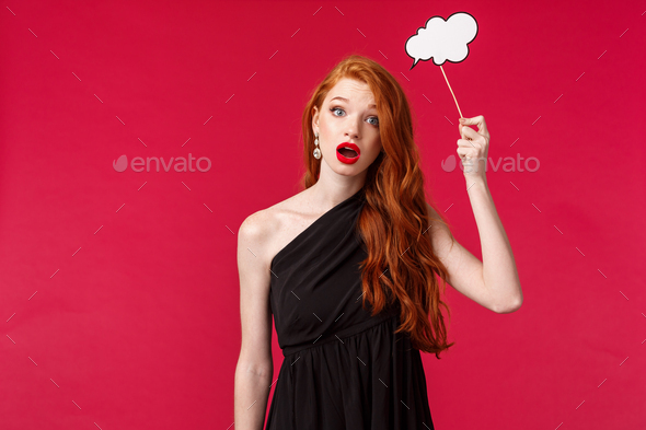 Portrait of clueless and indecisive attractive feminine redhead woman in black dress, holding cloud