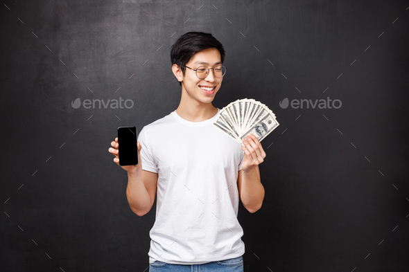 Technology, money and prizes concept. Pleased smiling happy rich asian guy in t-shirt, looking