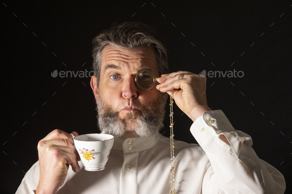 Man with muttonchops and funny expression holding monacle and cup of tea. - Stock Photo - Images