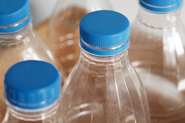Plastic bottles with blue caps for recycling in a wooden box.