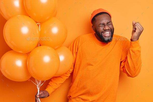 Overjoyed male student celebrates success makes yes gesture being on graduation party holds inflated