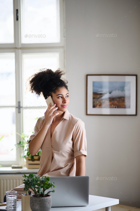 Happy young woman with smartphone working indoors at home, home office concept.