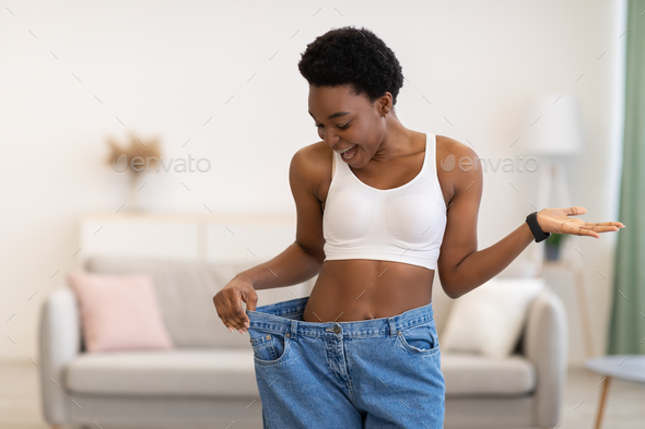 Happy fit woman with big pants, showing how much weight she lost. isolated  on white Stock Photo - Alamy