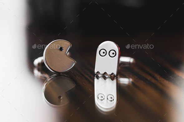 Cufflinks in Pacman shape close-up on wooden texture. Funny style pac man