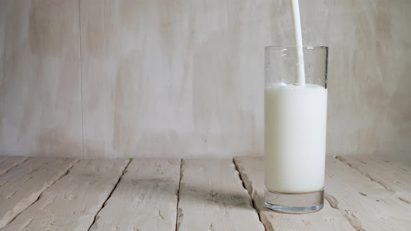 Pour Yogurt Into A Glass On White Vintage Wooden Boards. Milk Drink In A Transparent Glass. alt