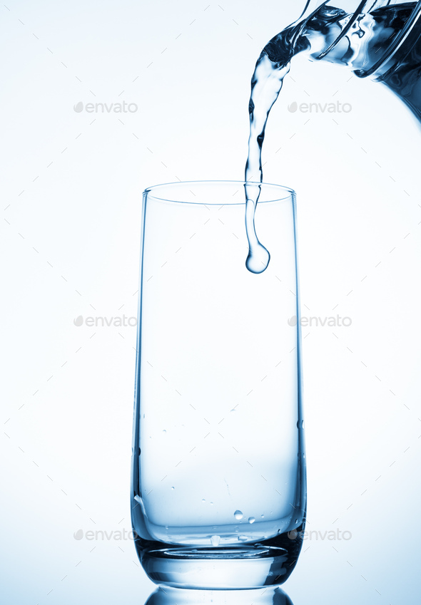 Pouring water from glass pitcher on blue background Stock Photo by natika