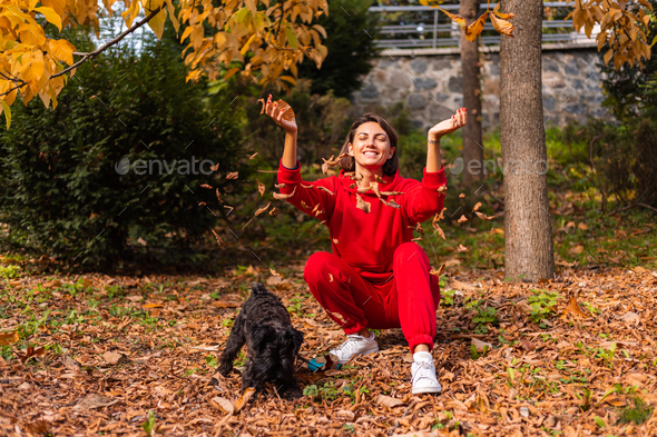 Early morning. Happy woman sleepy eyes with dog in park, autumn orange yellow colors.