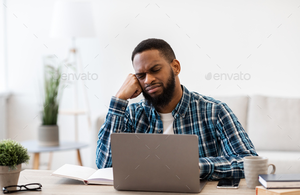 Bored Black Guy Sitting At Laptop In Modern Office