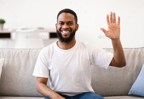 Happy Black Guy Waving Hand To Camera Posing At Home