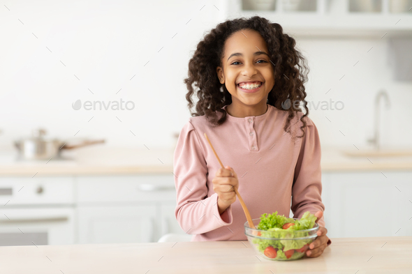 Cheerful african american girl preparing healthy salad Stock Photo by  Prostock-studio