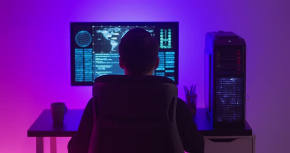 Rear View of Man Programmer Enjoying While Working at a Computer at Night alt
