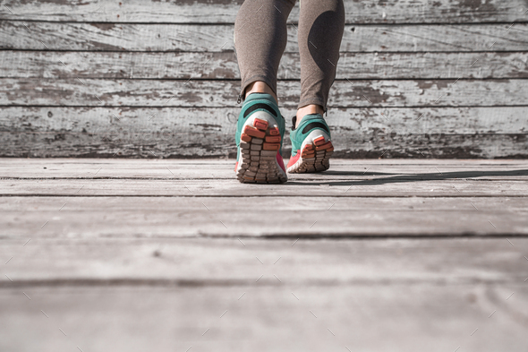 female legs in sneakers on a wooden background