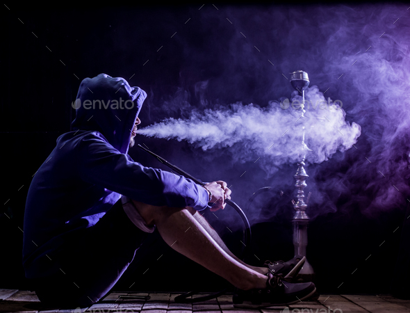 a man smokes a hookah on a black background, beautiful lighting Stock Photo  by puhimec
