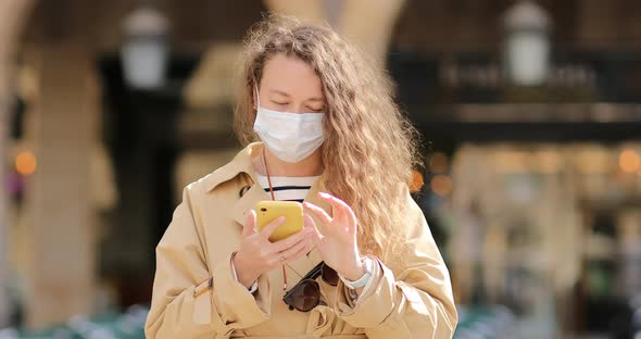 beautiful young woman with long curly hair is wearing sunglasses and using cellphone. 