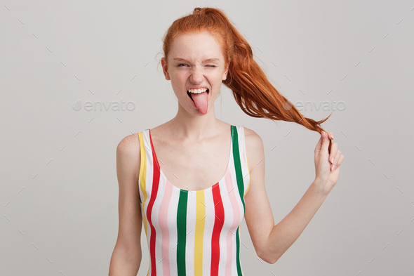 redhead young woman with freckles and ponytail wears striped top