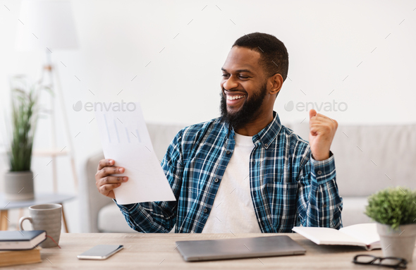 Happy African Businessman Reading Papers And Shaking Fists In Office
