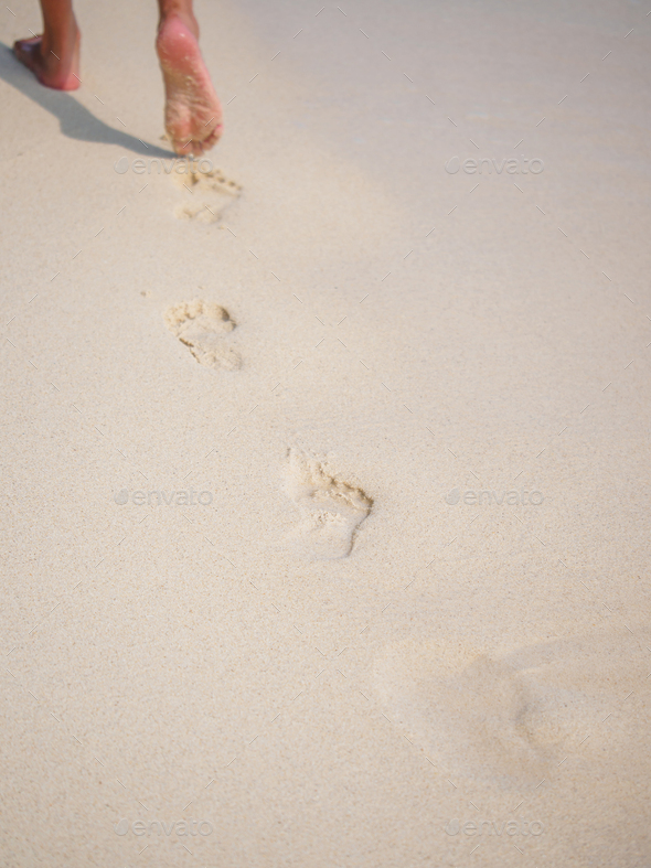 woman walking on sand beach leaving footprints in the sand. Stock Photo ...