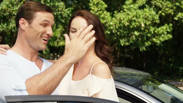Couple interacting with each other near car alt