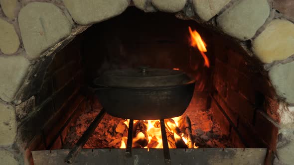 Cooking Food in the Oven on an Open Fire. Cast-iron Cauldrons with Food. Firewood and Fire in the