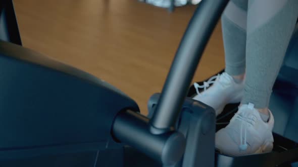 Woman Legs Training on Elliptical Machine in Gym Closeup. Cardio Workout