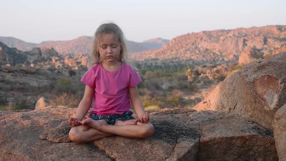 Little Cute Girl Meditating on Top of Mountain