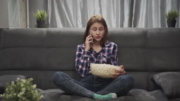 Young Caucasian Woman Is Talking Phone While Sitting on Sofa in Home Interior.