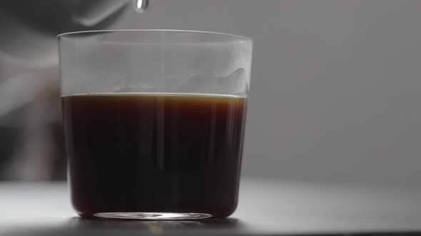Slow Motion Pour Water in Coffee in Tumbler Glass on Concrete Countertop with Copy Space alt