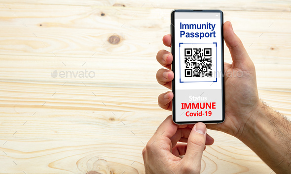 Immunity passport, coronavirus travel smartphone application on wooden background