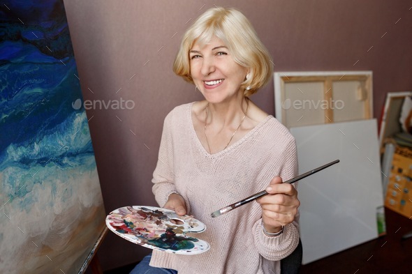 Happy Mature Artist Woman Painting On Canvas At Her Home Studio Stock Photo By Ssvetasokolova