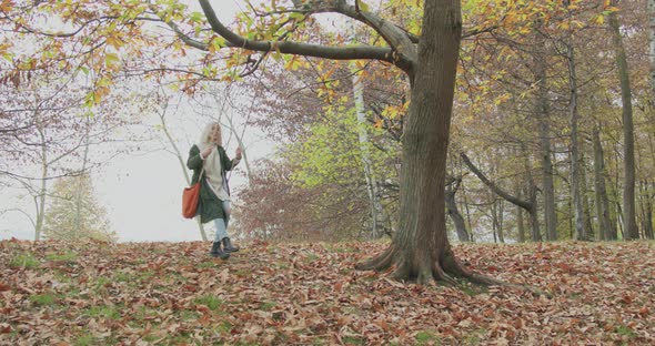 Slow Motion Approach of a Young and Lonely Woman Sitting on a Swing Under a Big Tree. Young Woman alt