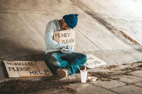 Beggars sitting under the bridge with a sign, please money.