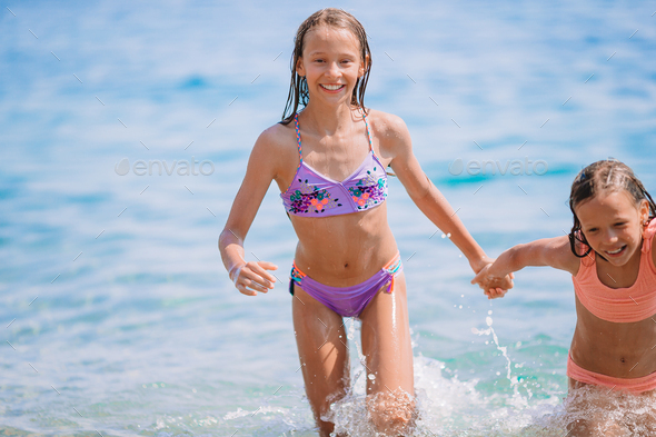 Adorable little girls having fun on the beach Stock Photo by