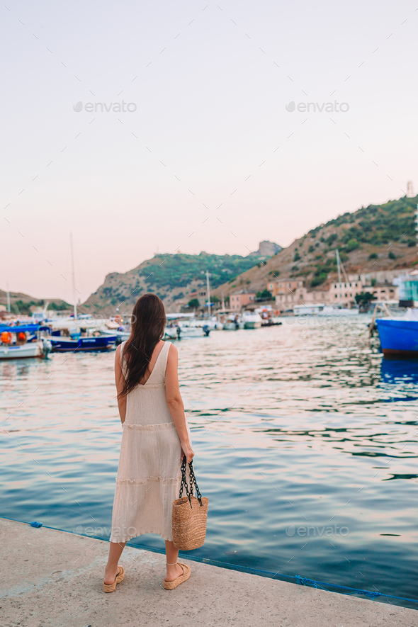 Young beautiful woman walking on dock near the boat