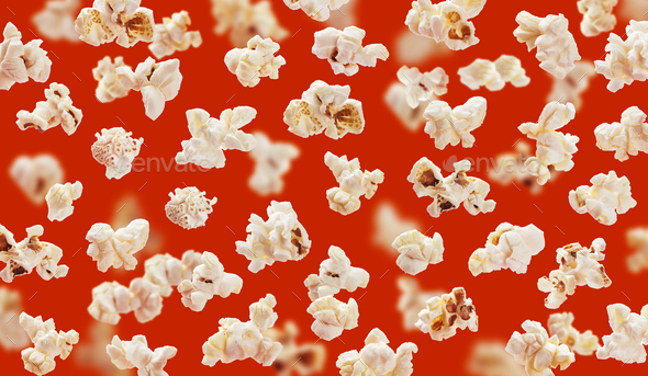 Delicious pop corn grains closeup on red background