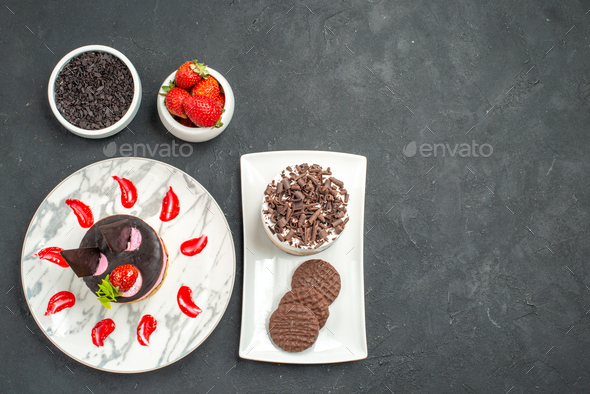 top view chocolate cake and biscuits on white rectangular plate and strawberry cheesecake on white